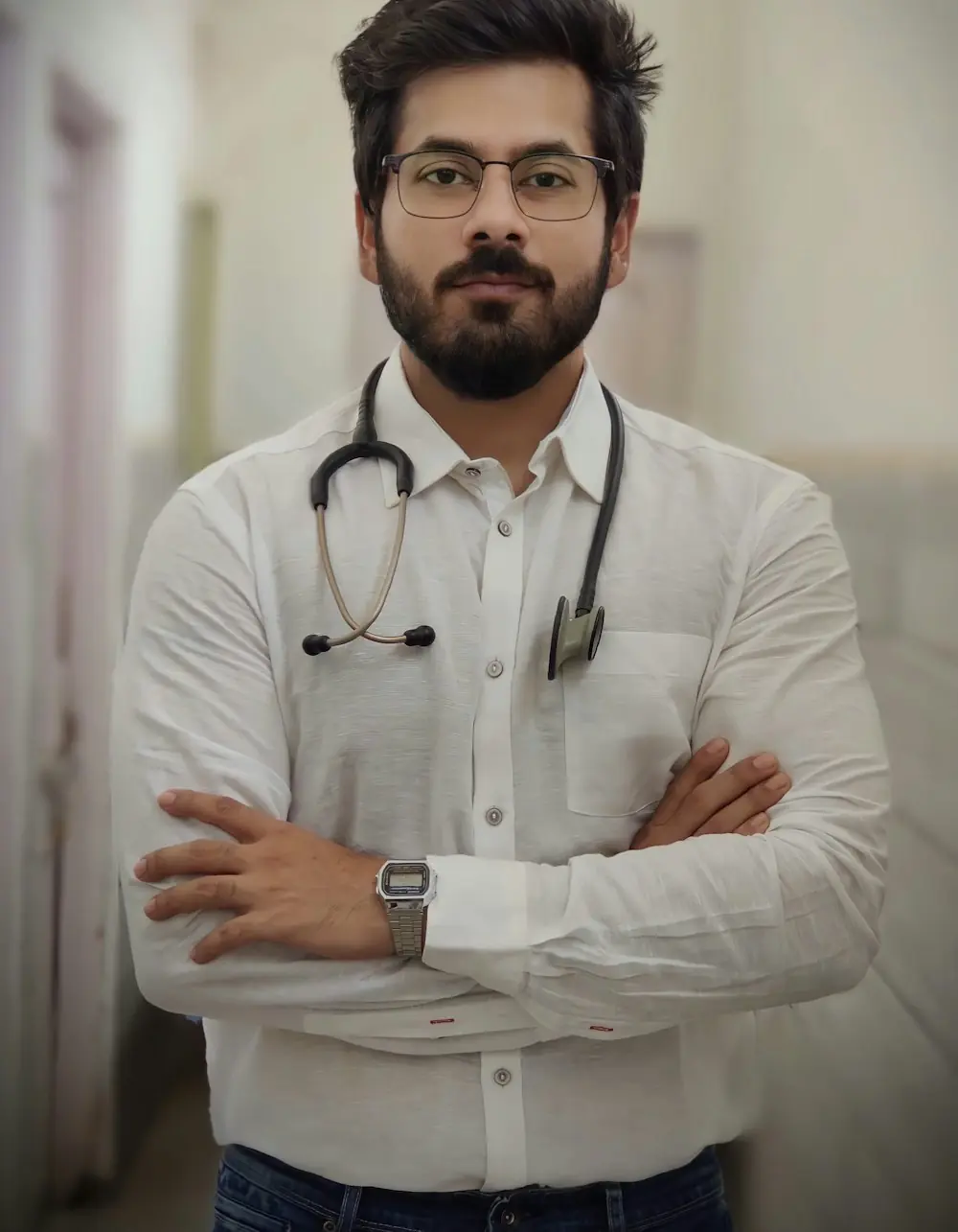 A doctor in a white shirt with a stethoscope around his neck, arms folded